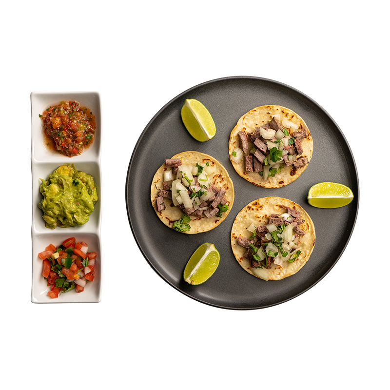Carne asada tacos with side plate containing salsa, guac, and pico de gallo from All in Meals